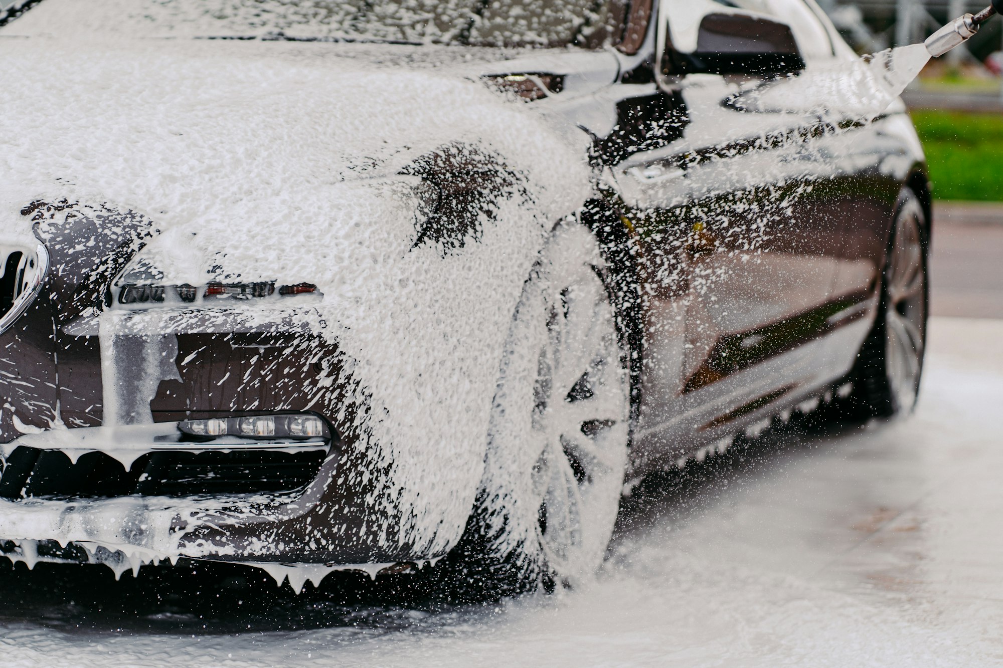 Car in white foam. Washing vehicle. Carwash. Transportation covered with soap