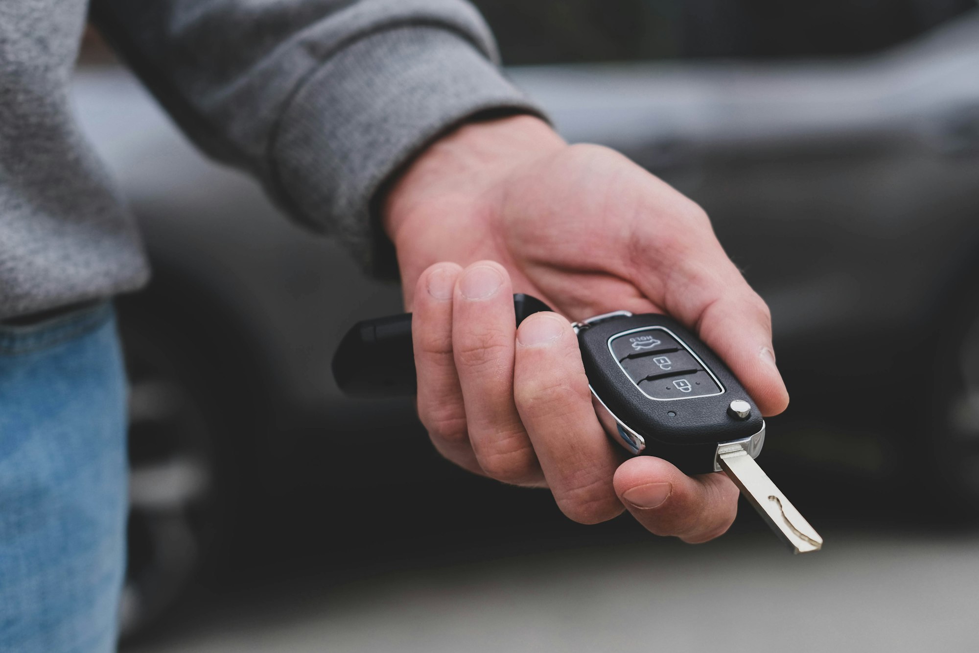 Man in front of the new car and holding keys. Salesman is carrying the car keys delivere